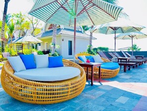Una piscina al aire libre, sombrillas, sillones reclinables de piscina