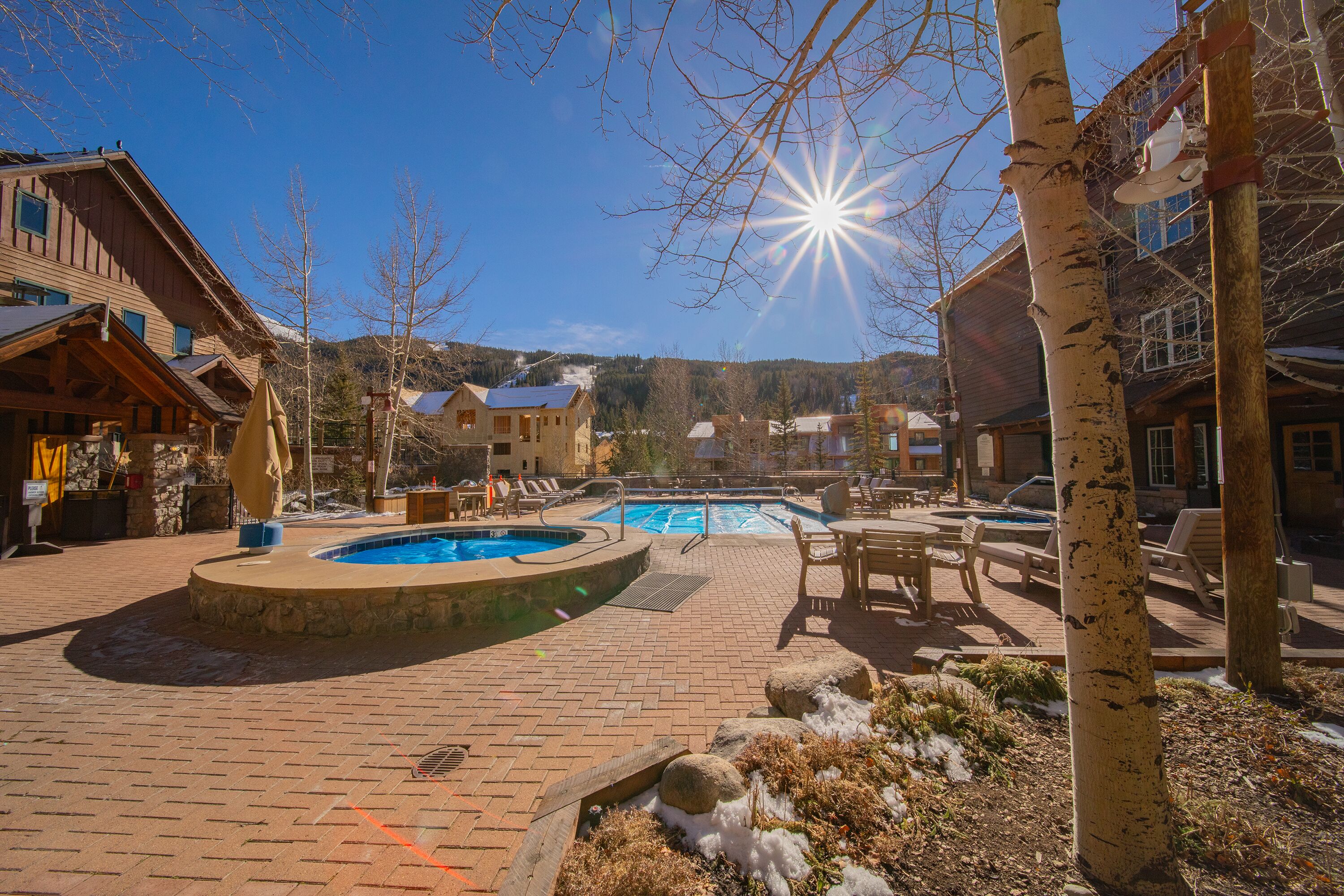 A pool area with a hot tub, lounge chairs, and a wooden building.