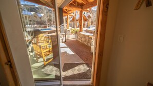 A wooden balcony with a glass door leading to a pool area. - Dakota Lodge 8450 (Keystone)