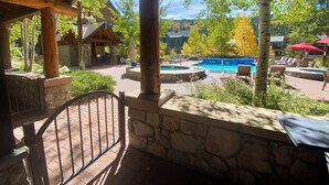 A wooden deck with a stone wall, a pool, and lounge chairs. - Dakota Lodge 8450 (Keystone)