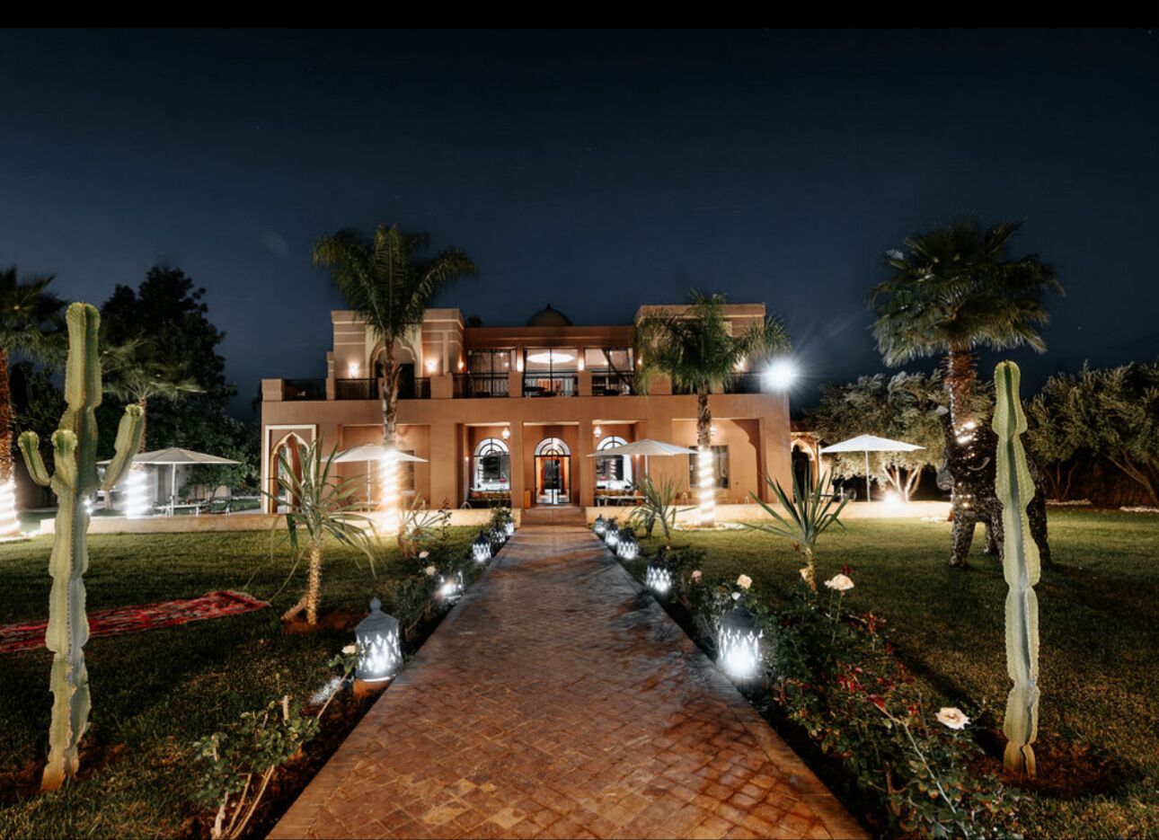 A large, well-lit building with a central courtyard, surrounded by cacti and palm trees.