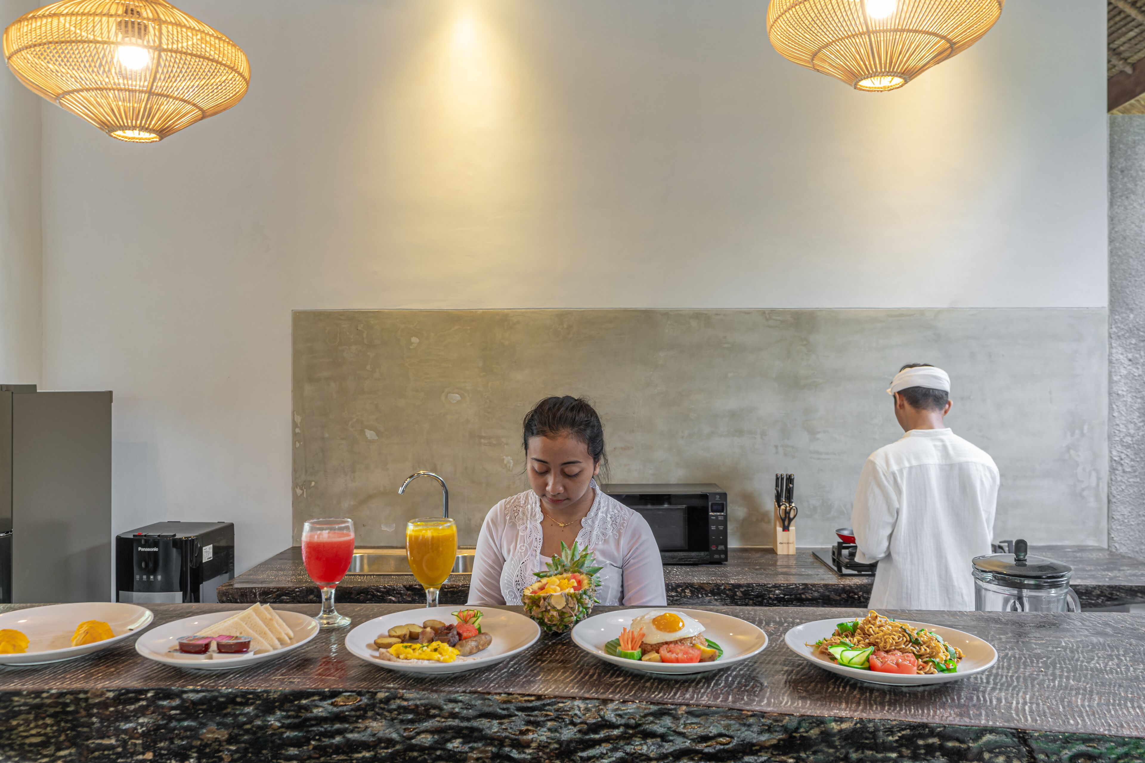 A breakfast setting with plates of food, a fruit, and a drink.