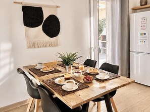 Un coin repas avec une table en bois, des chaises, une plante et des aliments pour le petit-déjeuner.