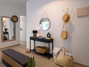 Un intérieur moderne comprenant une console, un miroir, un panier en osier, un banc et un porte-chapeaux fixé au mur.