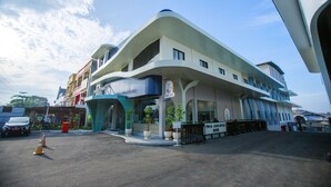 A modern hotel with a curved facade, multiple balconies, and a cafe area.