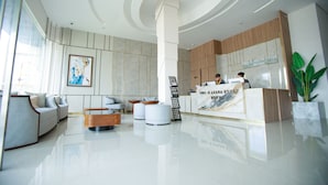 A modern hotel lobby with a reception desk, seating area, and artwork on the walls.