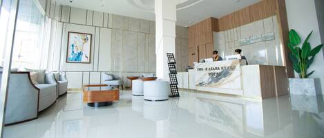 Una hall moderna di un hotel con reception, area relax e opere d'arte alle pareti.