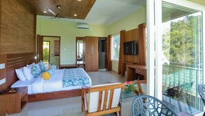 A modern bedroom with a large bed, wooden headboard, a TV, and a balcony with a glass railing. - Aveda Munnar Mountains and Mist (Devikolam)