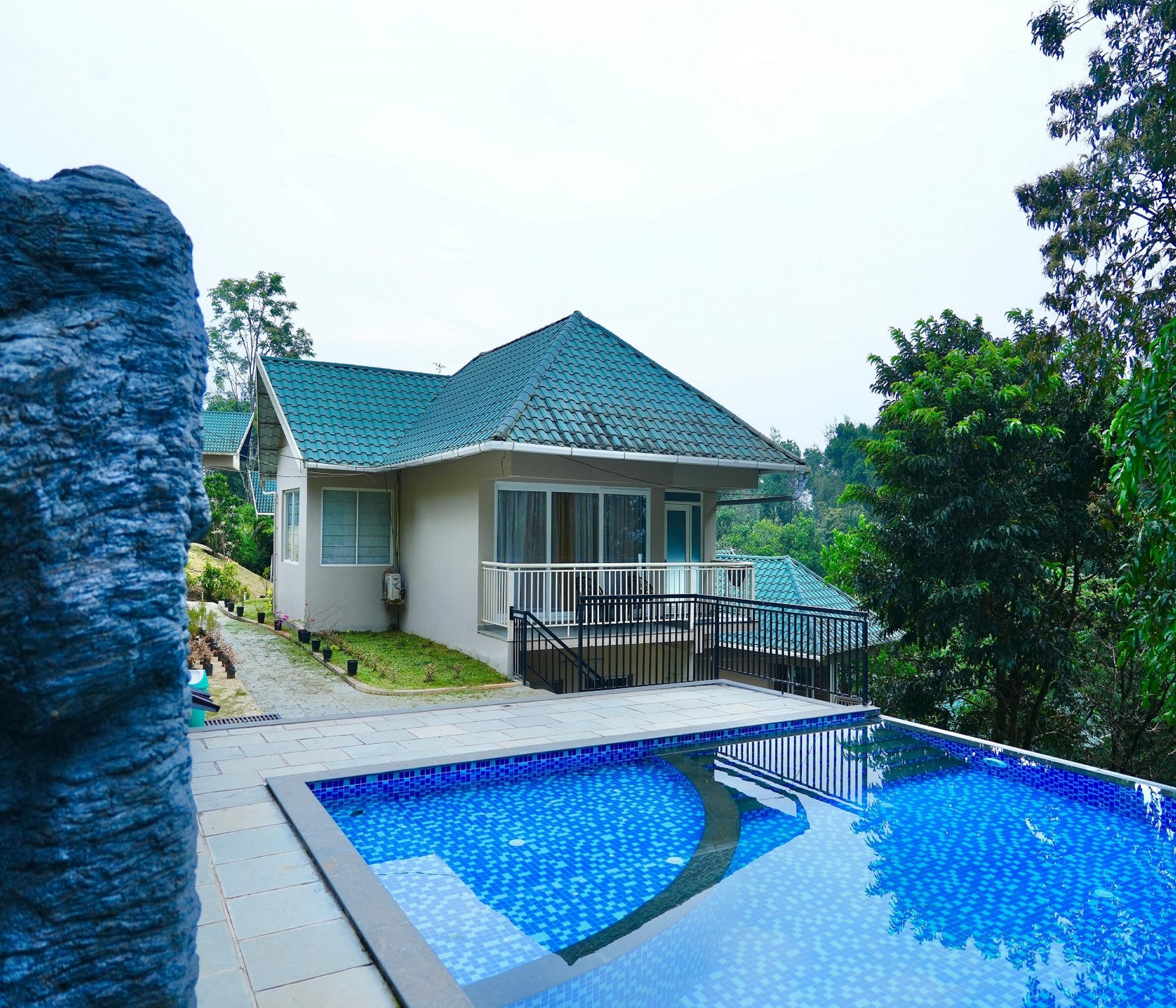 A house with a swimming pool, a balcony, and a stone wall.