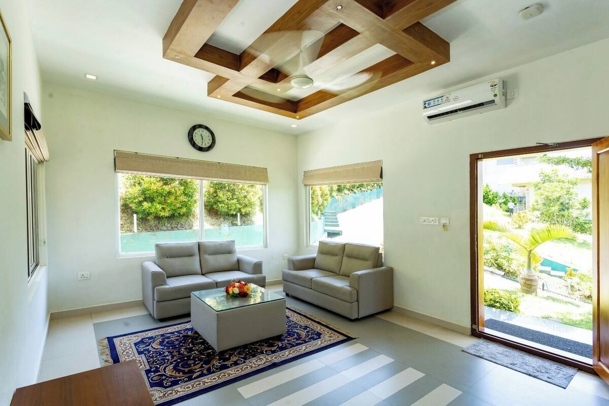 A modern living room with two sofas, a coffee table, and a large window with a view of greenery.