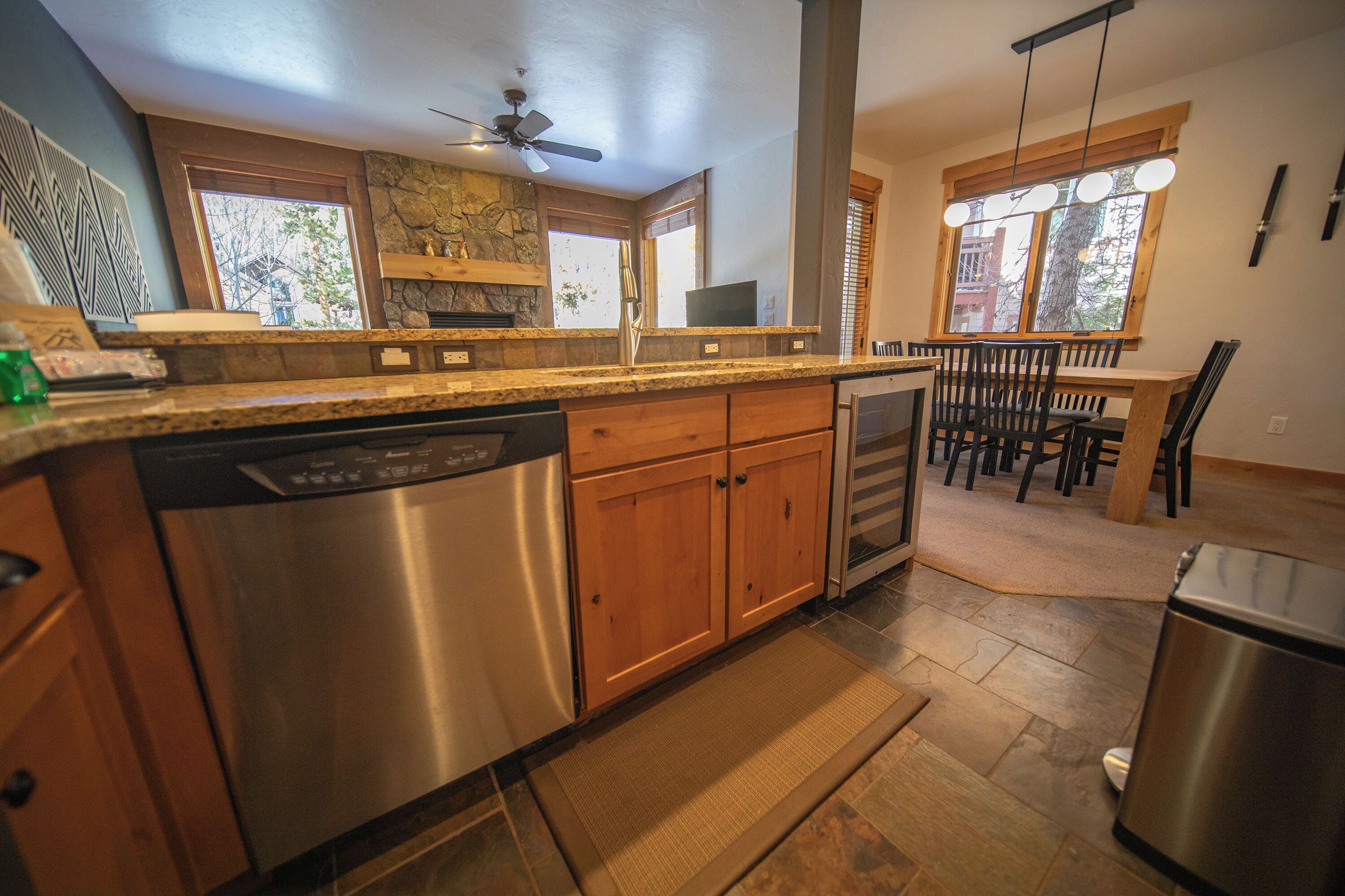 A modern kitchen with granite countertops, stainless steel appliances, wooden cabinets, and a dining area with a table and chairs.