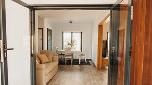 A modern living room with a sofa, a dining table, and chairs. - A tranquil 40 acre olive grove, comfort inside, fire pit & hot tub outside  (Clare)