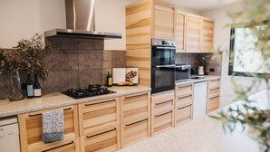 A modern kitchen with wooden cabinets, a stainless steel range hood, and a built-in oven. - A tranquil 40 acre olive grove, comfort inside, fire pit & hot tub outside  (Clare)