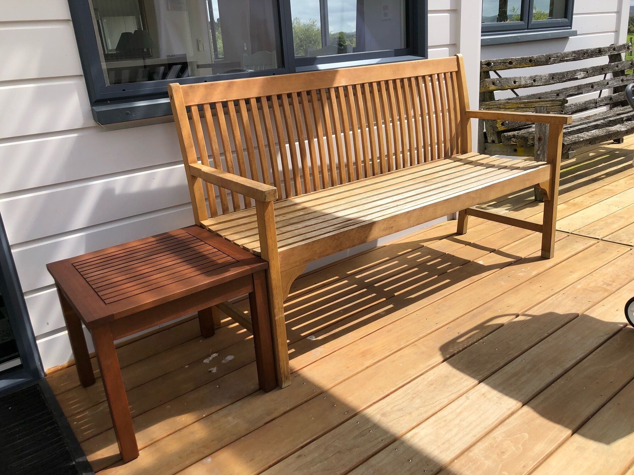 Un banc et une table en bois, installés sur une terrasse en bois.