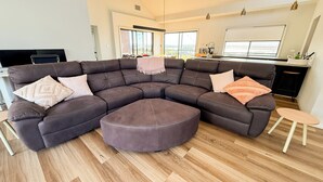 A modern living room with a sectional sofa, ottoman, and a small wooden table. - Marbles Riverview House (Pet Friendly) Sleeps 10 (Hindmarsh Island)