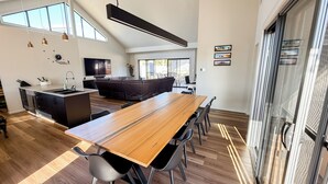 A modern kitchen with a wooden dining table, built-in appliances, and a large window. - Marbles Riverview House (Pet Friendly) Sleeps 10 (Hindmarsh Island)