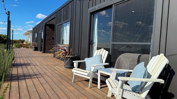 A wooden deck with two Adirondack chairs and a potted plant. - Marbles Riverview House (Pet Friendly) Sleeps 10 (Hindmarsh Island)