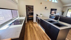 A modern kitchen with a central island, built-in appliances, and a wooden floor. - Marbles Riverview House (Pet Friendly) Sleeps 10 (Hindmarsh Island)