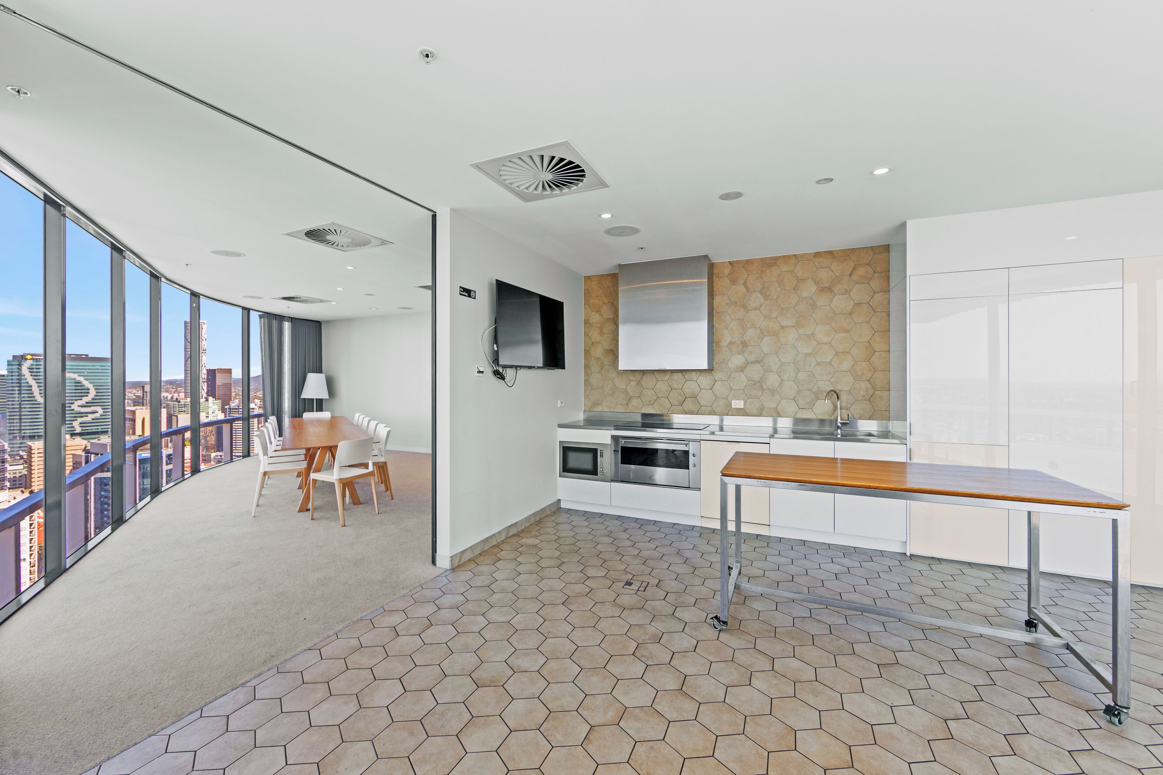 A modern kitchen with a large island, a dining area with chairs, and a view of the city through large windows.