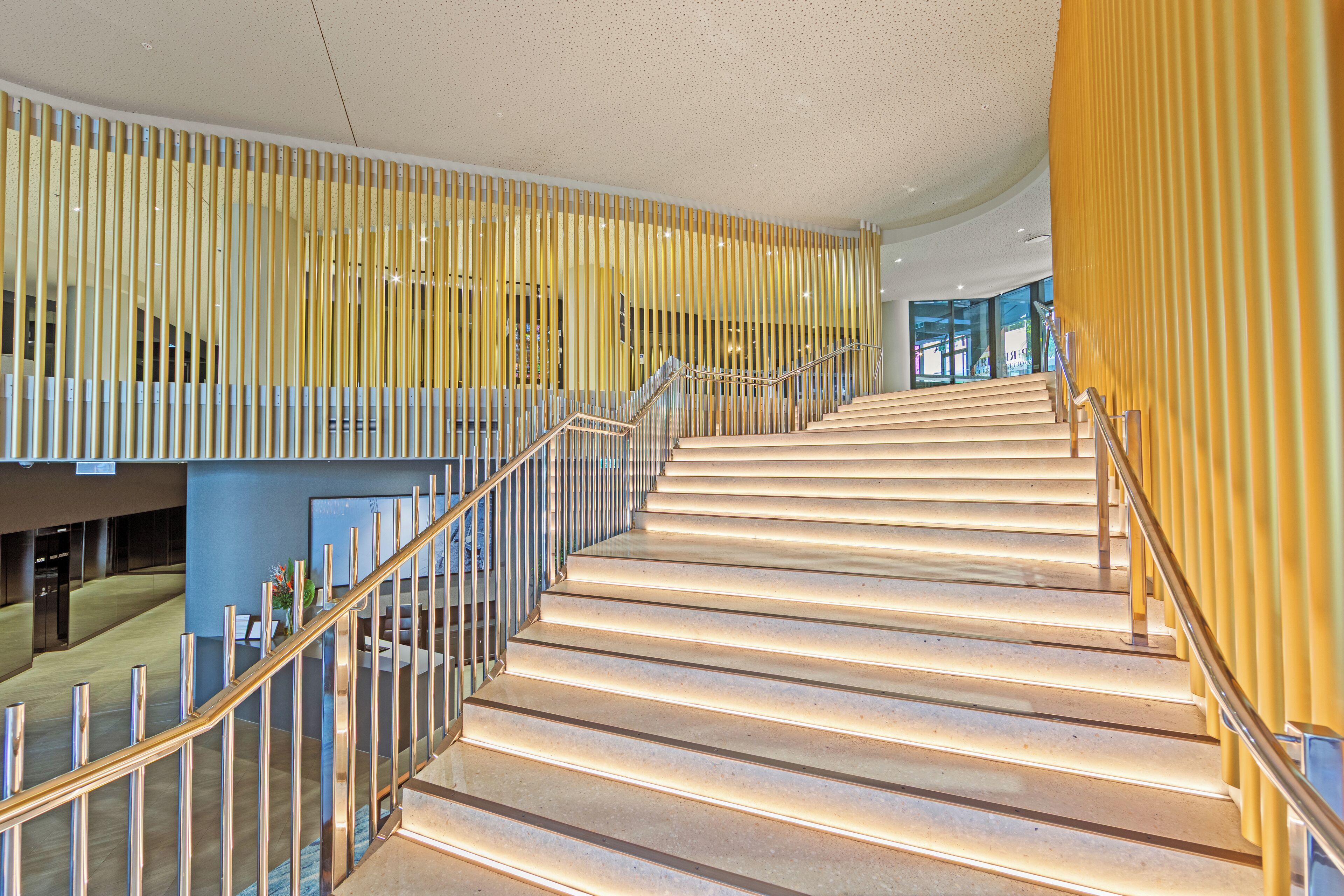 A modern staircase with a metallic railing and a yellow accent wall.