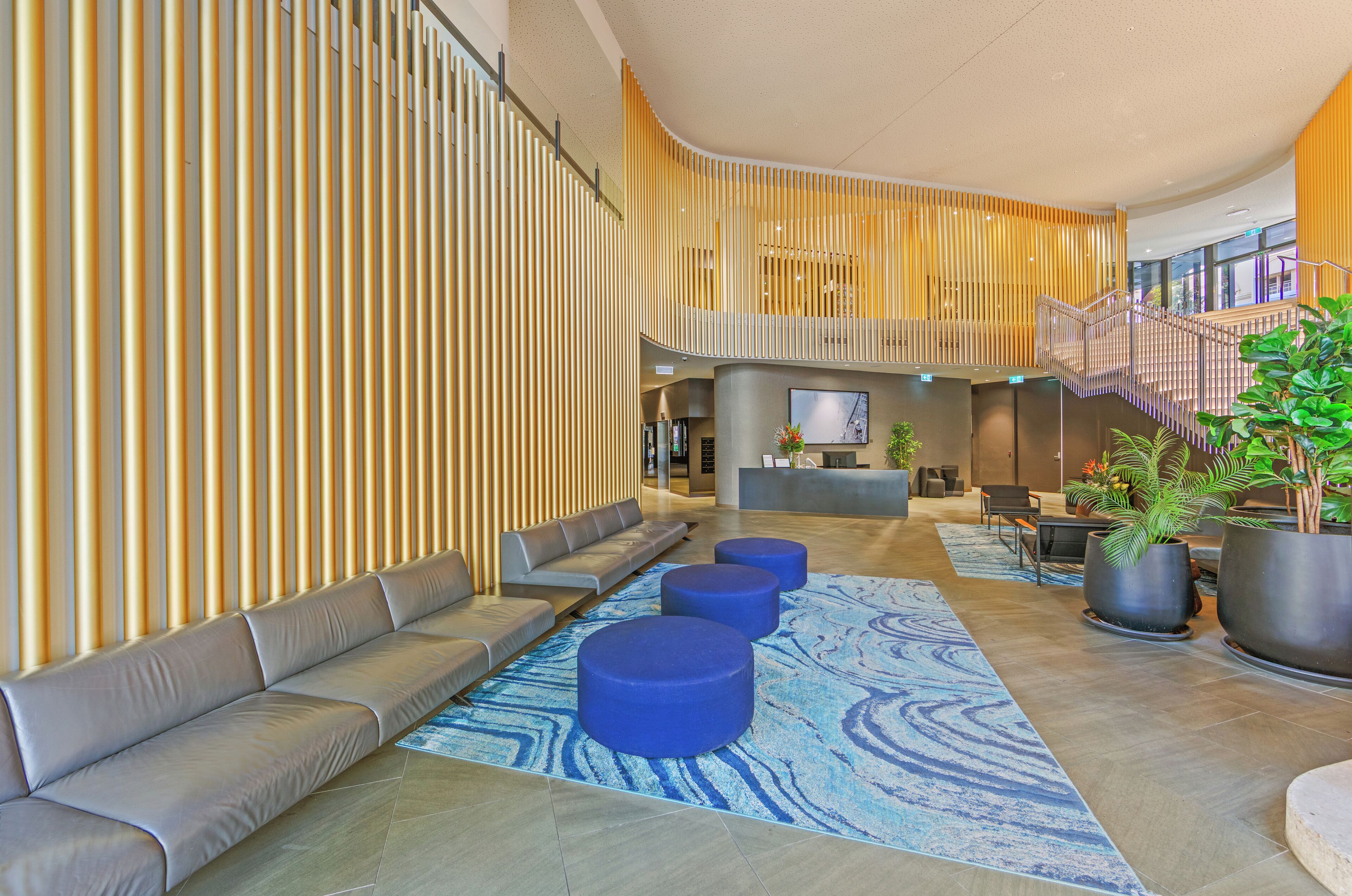 A modern lobby with a curved seating area, a reception desk, and a staircase.
