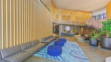 A modern lobby with a curved seating area, a reception desk, and a staircase.