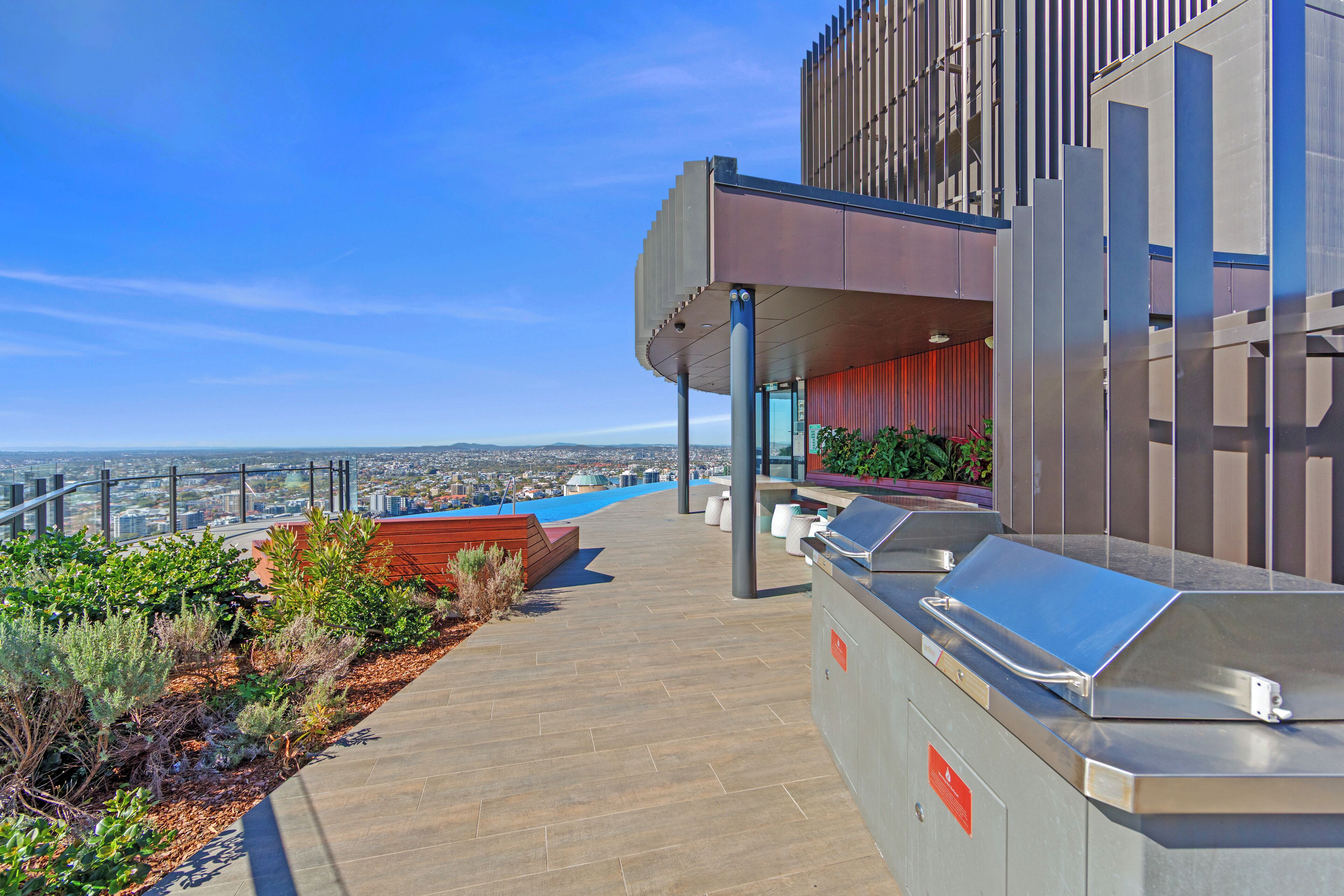 A rooftop terrace with a view of the city, a seating area, and a modern building structure.