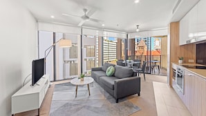 Un apartamento moderno con sofá, televisor, zona de comedor y cocina.