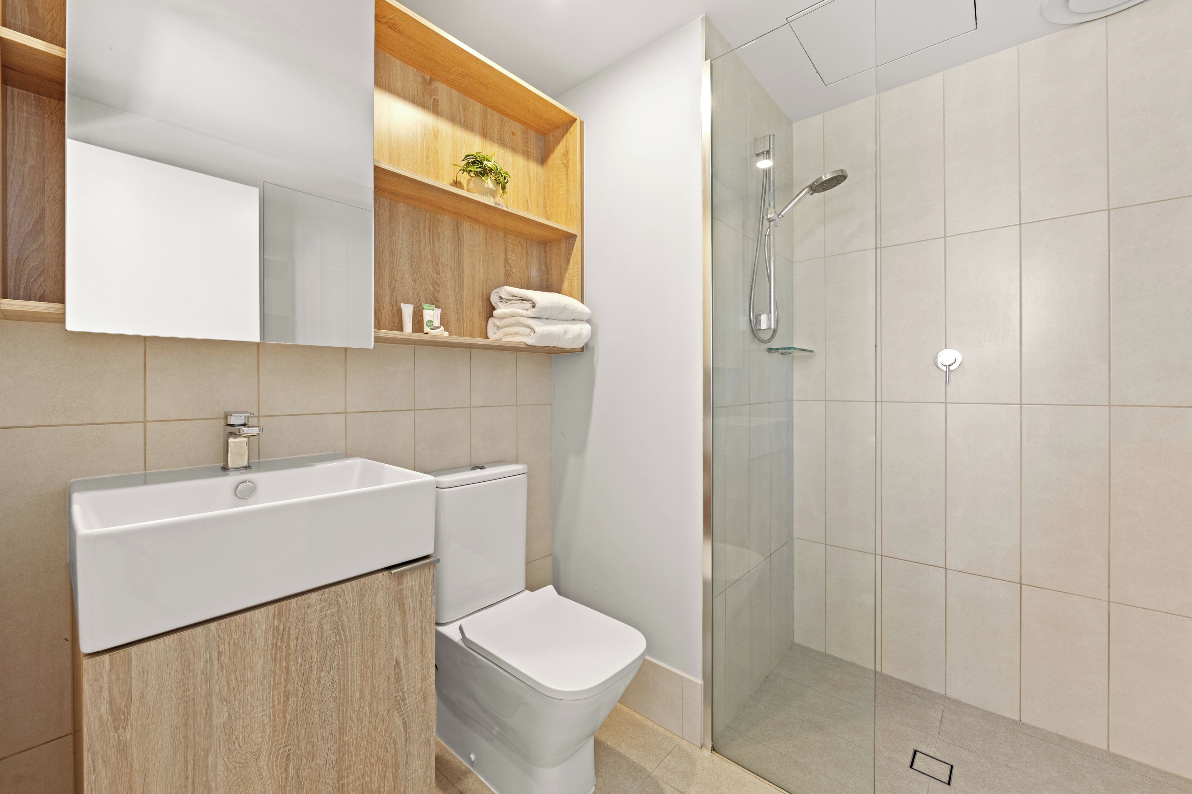 A modern bathroom with a sink, toilet, and glass-enclosed shower.