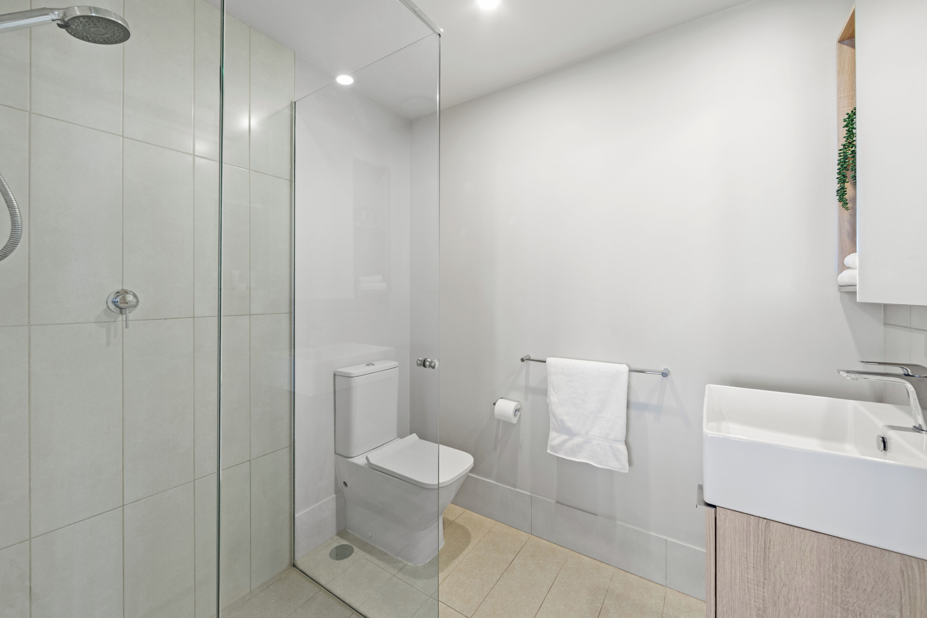 A modern bathroom with a glass shower enclosure, a toilet, a sink, and a towel rack.
