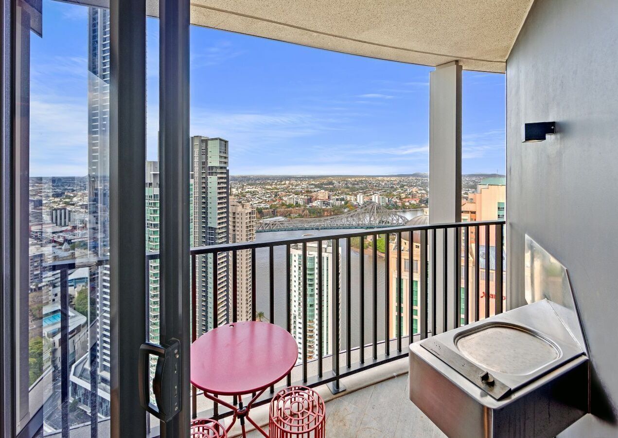 A balcony with a table and a small sink, offering a city view.