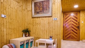 Una habitación de madera con una mesa, sillas, un cuadro en la pared y una puerta con diseño en zig-zag.