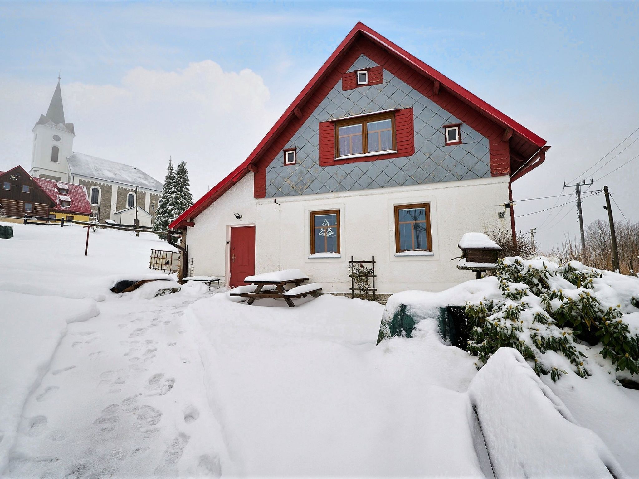 Ein zweistöckiges Haus mit rotem Dach und weißen Wänden, einer Holztür und einem Fenster mit Holzrahmen.