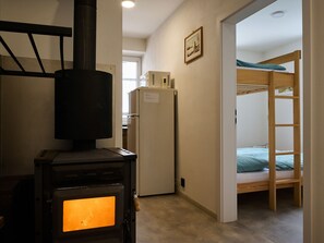 A compact room with a wood-burning stove, a refrigerator, and a bunk bed. - Jizerky Paws & Sauna by Interhome (Tanvald)