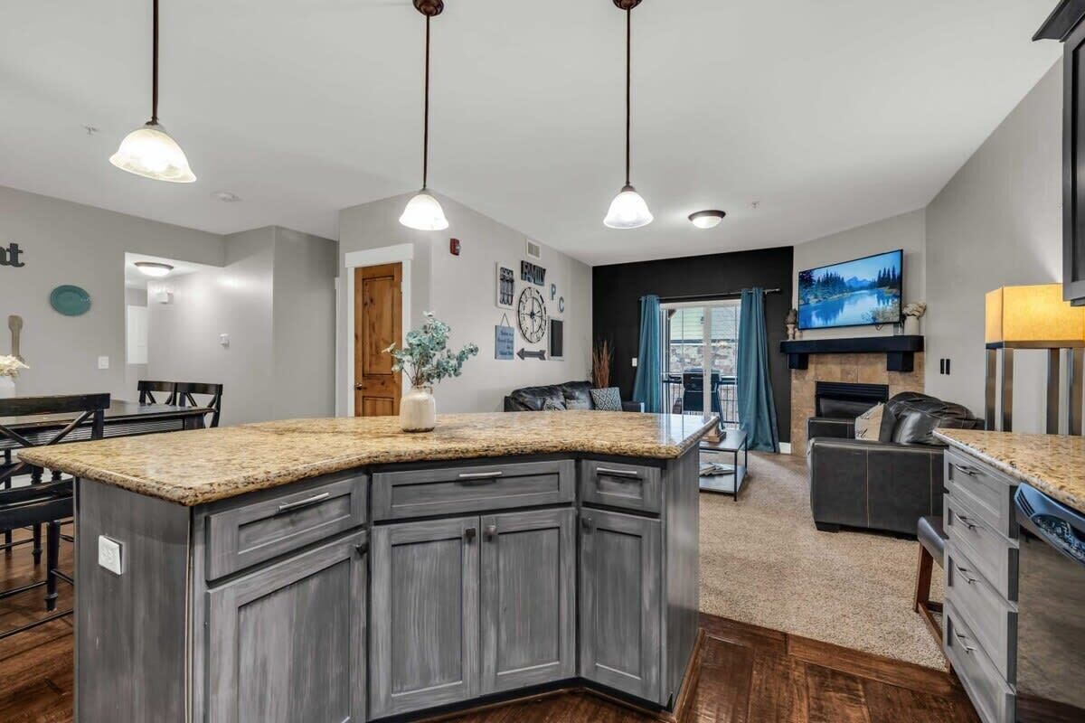 A modern kitchen with granite countertops, dark cabinetry, and pendant lighting.