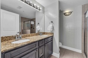 Une salle de bain moderne avec deux lavabos, un grand miroir et un espace douche.