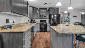 A modern kitchen with granite countertops, stainless steel appliances, and dark cabinetry. - 3BD Olympic Park Condo on FREE Shuttle Line (Park City)