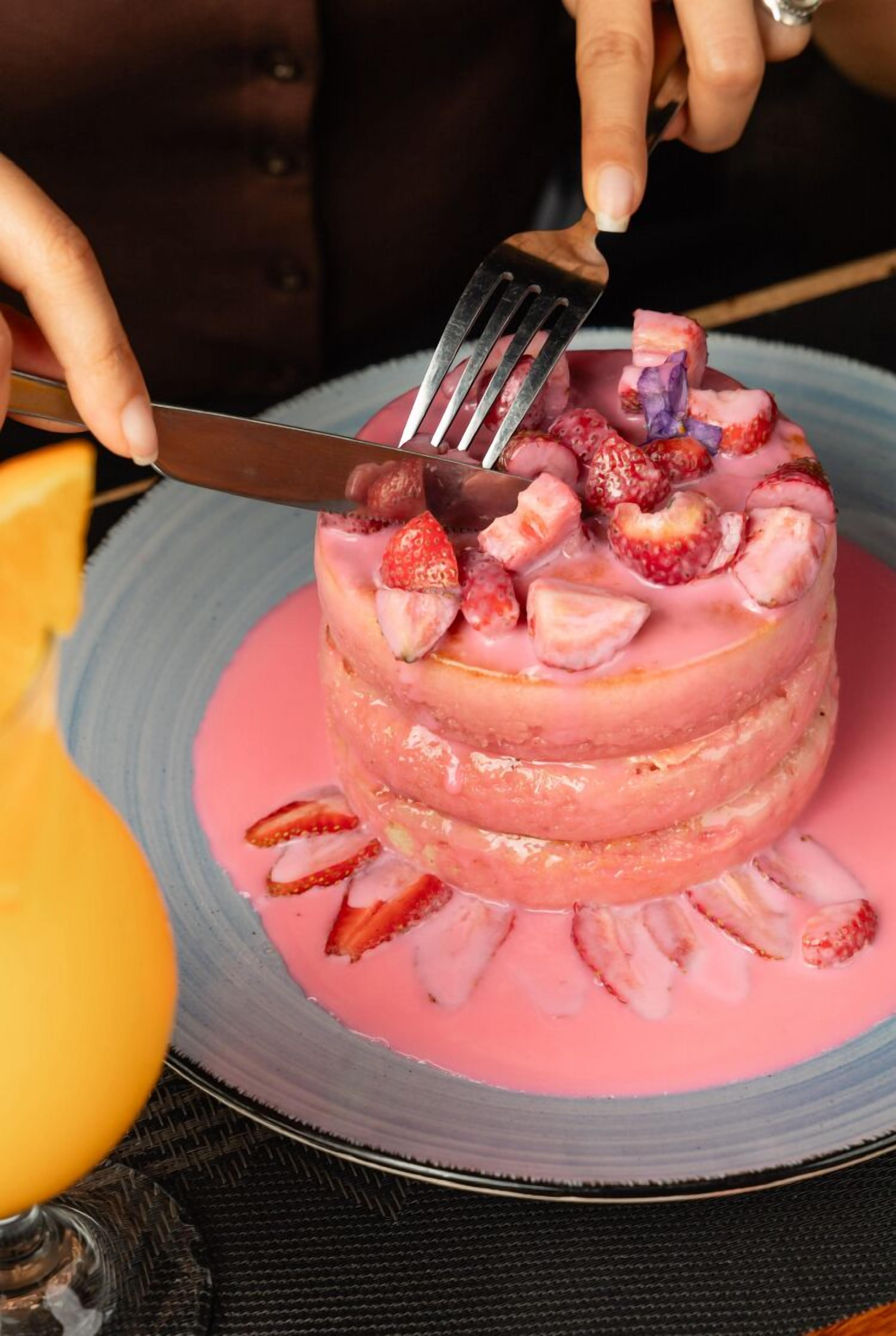 A cake with strawberries and a fork on a plate.