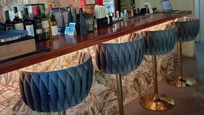 A bar area with a long counter, multiple bottles of alcohol, a laptop, and bar stools. - Boquete Firefly Inn (Los Naranjos)