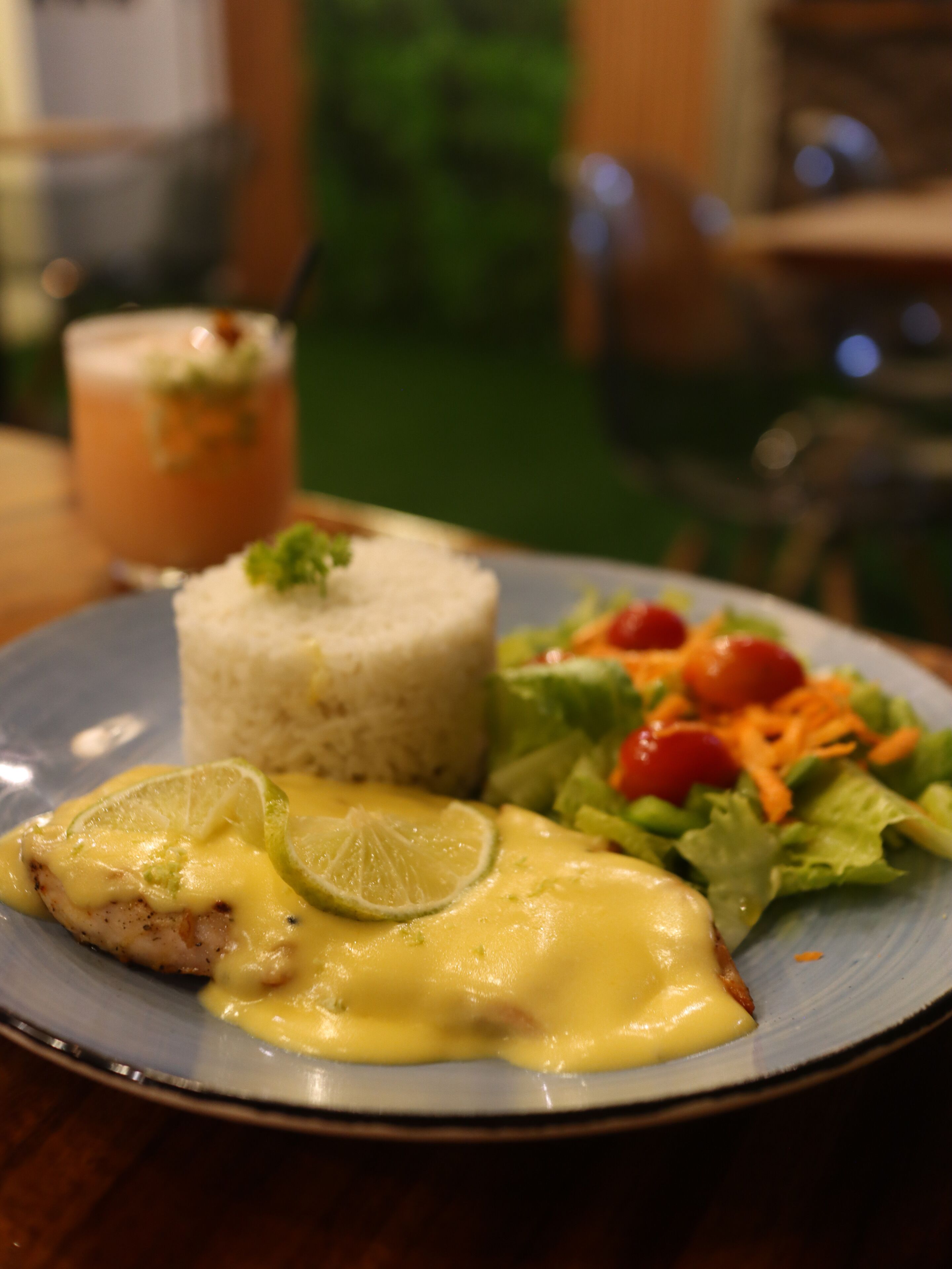 A plate with rice, a salad, and a piece of meat with sauce.