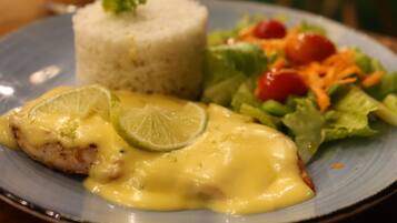 Un plato de arroz, ensalada y un trozo de carne con salsa.