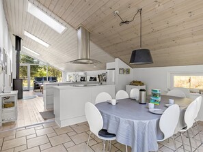 Une cuisine moderne dotée d’un îlot central, de meubles blancs et d’un coin repas avec une table et des chaises.