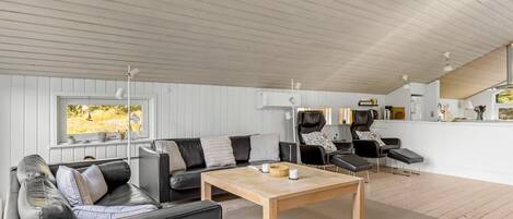 A modern interior with a wooden ceiling, a sofa, a table, and two massage chairs.