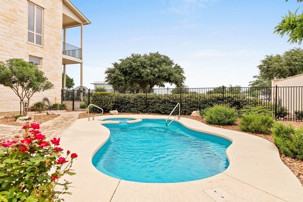 A swimming pool with a curved edge, surrounded by a concrete deck. - Southern Charm at Gruene Silo – Private King Suite w/ Shared Pool, Porch & Spacious Living Room (New Braunfels)