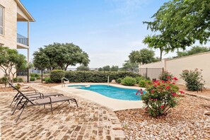 A swimming pool with lounge chairs, surrounded by a garden with trees and shrubs. - Southern Charm at Gruene Silo – Private King Suite w/ Shared Pool, Porch & Spacious Living Room (New Braunfels)