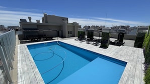 A rooftop pool with a wooden deck, lounge chairs, and a view of the cityscape. - Caballito Retreat Rooftop Pool and Balcony (Buenos Aires)