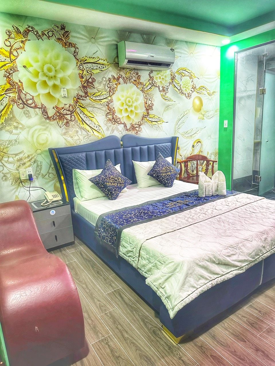 A bedroom with a bed, bedside table, and a red chair.