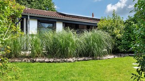 Ein modernes Haus mit Ziegeldach, umgeben von einem gepflegten Rasen und dichtem Grün.