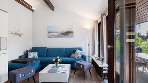 Ein modernes Wohnzimmer mit einem blauen Sofa, einem weißen Couchtisch und einem kleinen Tisch mit Blumen in einer Vase.