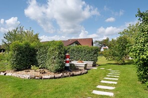 A garden with a pathway leading to a building with a red roof.